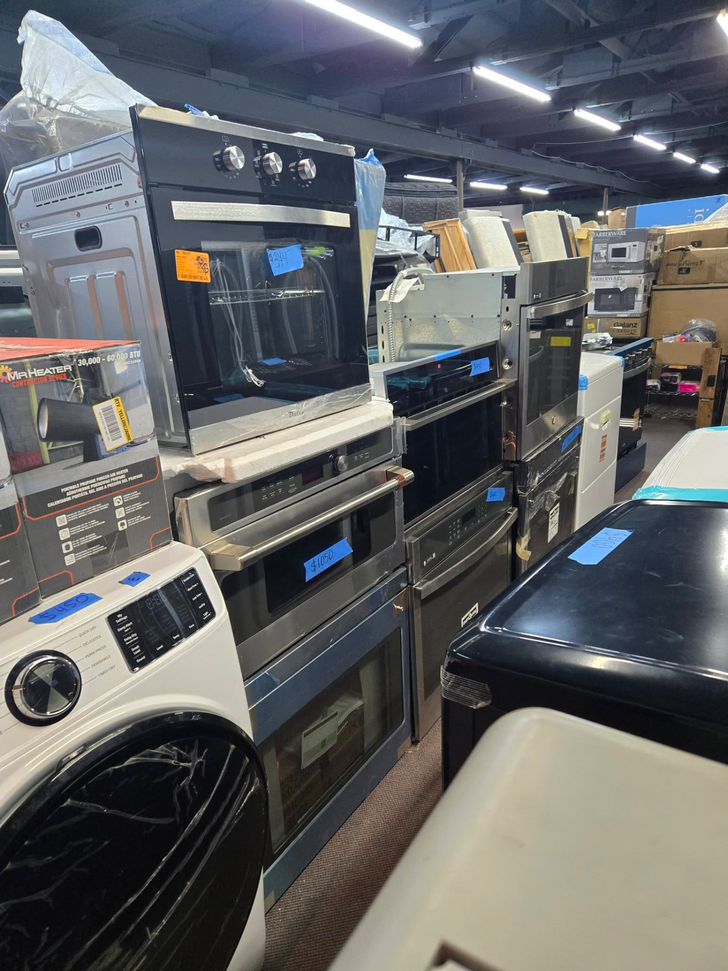 Wall ovens, microwaves and ranges stacked with handwritten price tags